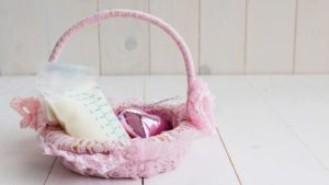 pink lace covered basket with a bag of baby formula in it