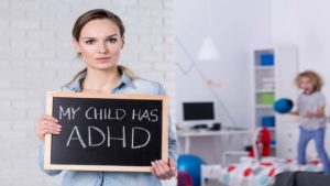 woman holding small chalkboard saying "My Child has ADHD"