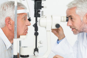 older doctor preforming eye exam on older patient