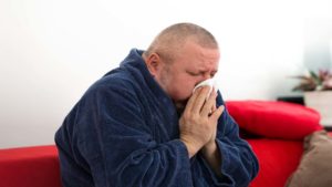 man with a cold blowing his nose